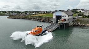 Moelfre lifeboat launching for training in June, with a splash as lifeboat enters.