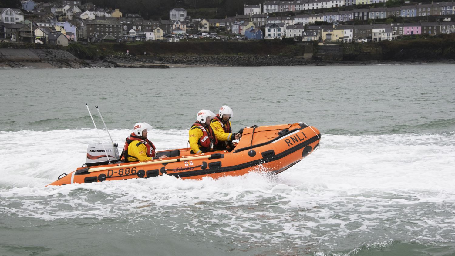 A lifeboat marked “RNLI 13-48” in calm grey water. 