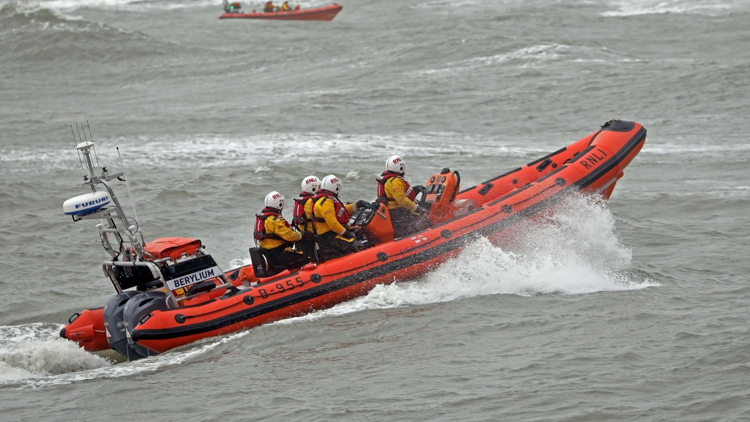 The Newcastle lifeboat going through spray on grey water.