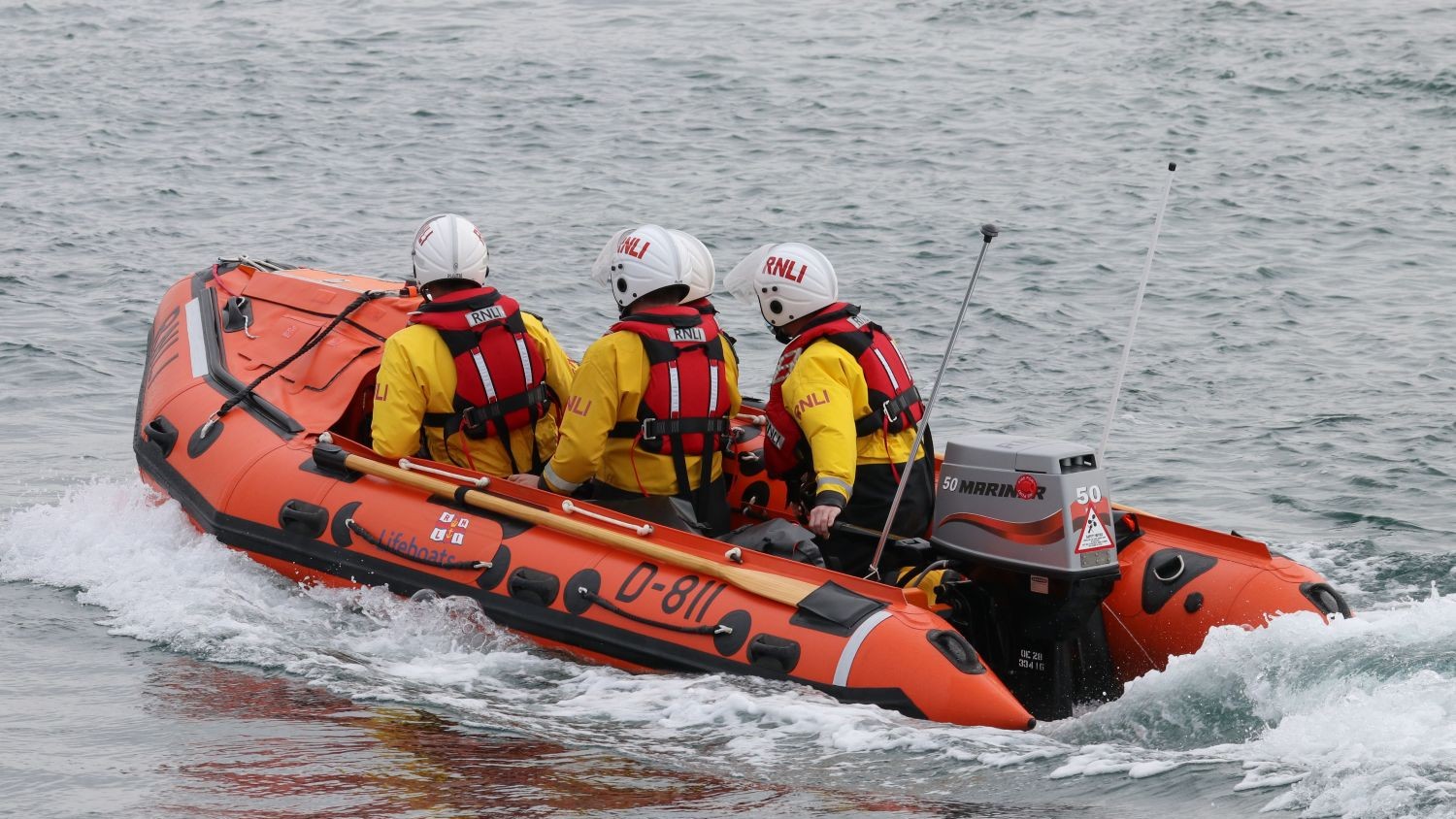 Pwllheli's D class lifeboat creating a wake in calm water.