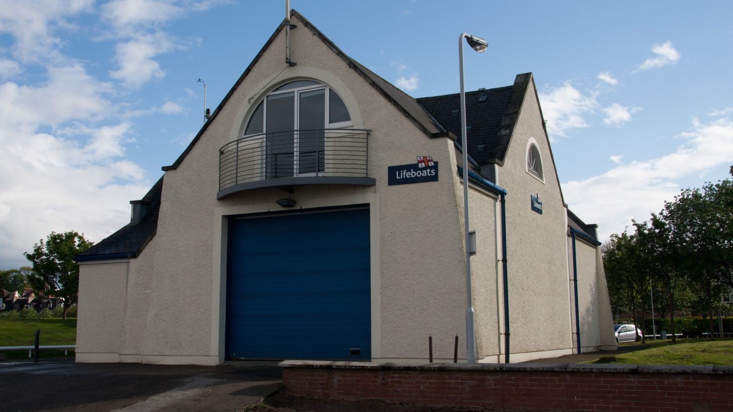 A two storey grey building with a large blue door into the boatshed.