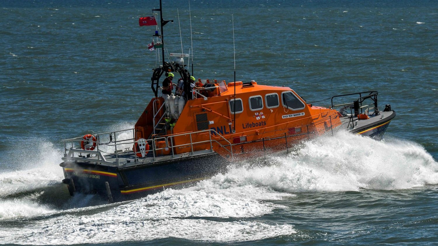 An Shannon all weather lifeboat powering through spray against a blue sea.