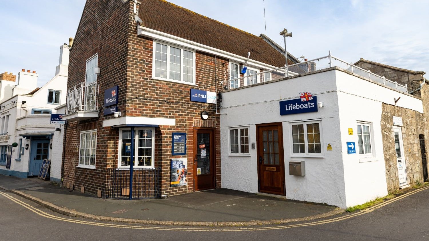 A one storey white building, next to a two-storey brick RNLI shop.