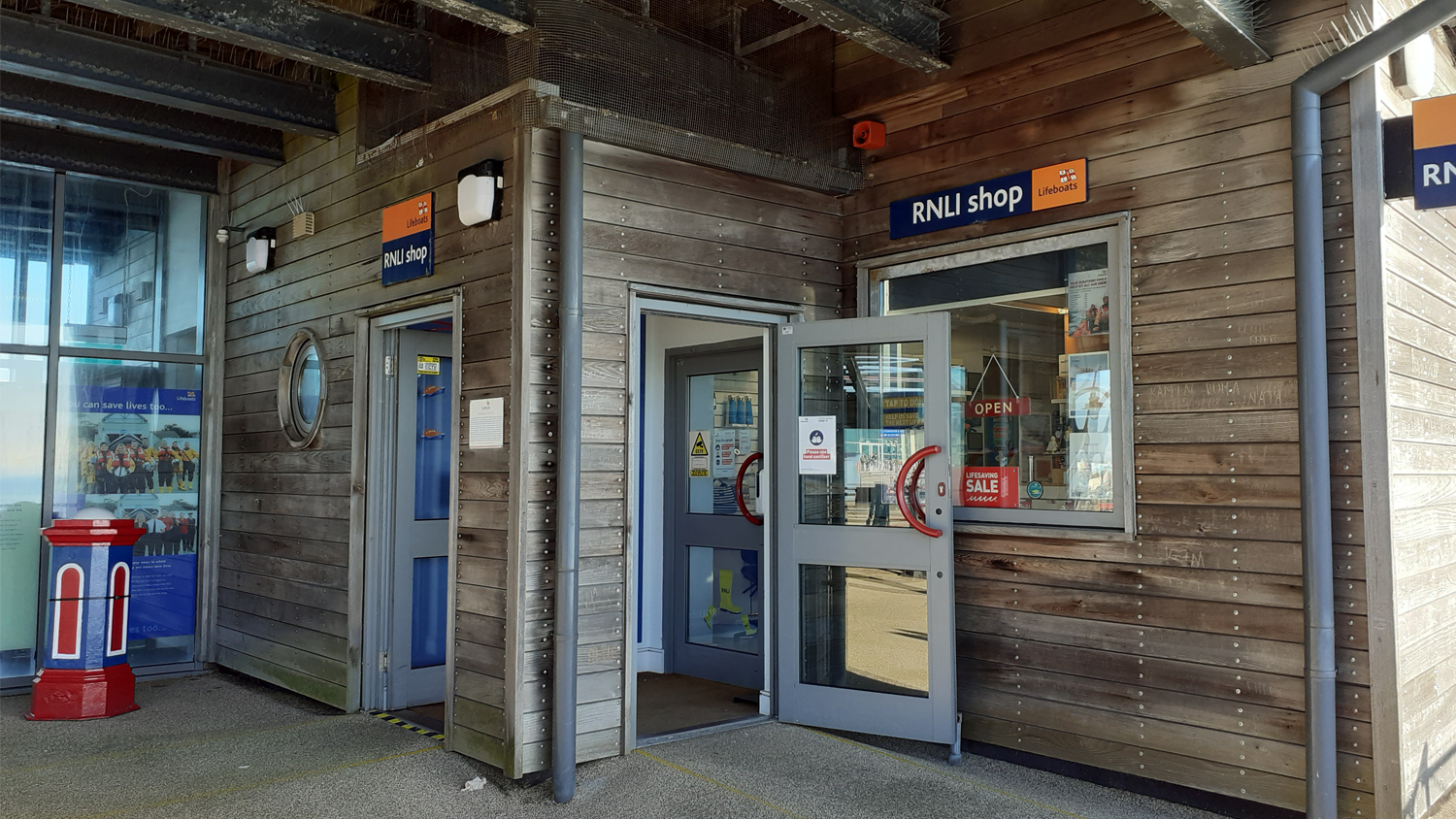A modern, wooden shop front with a porthole shaped window.