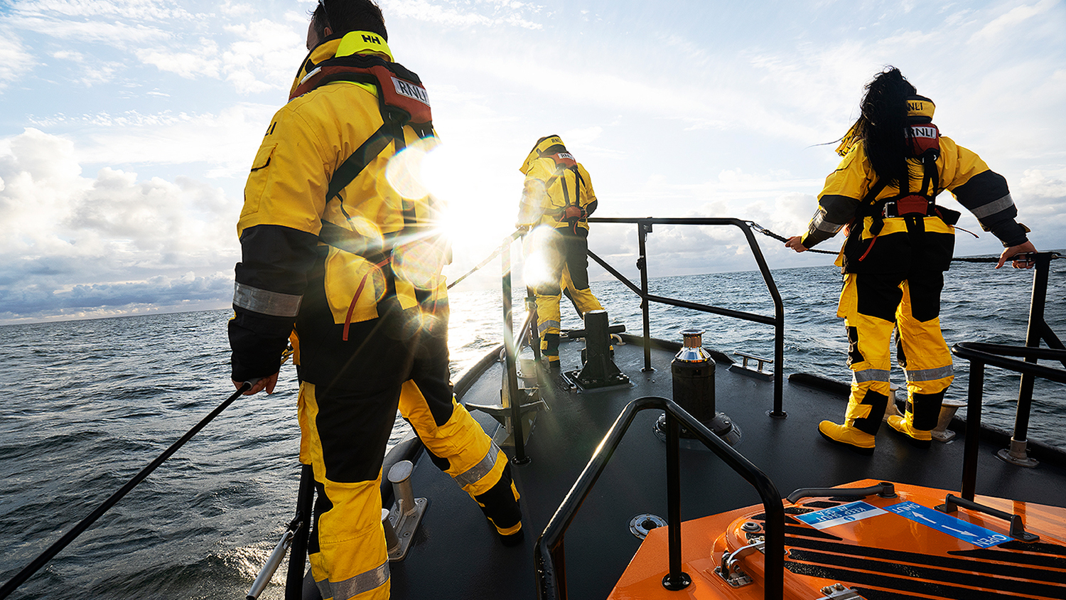 Three crew on the bow of Clifden RNLI's Shannon class lifeboat, looking out to sea.