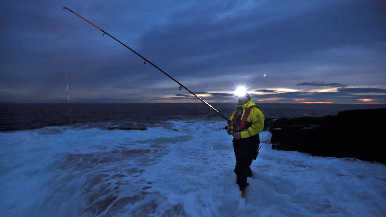 Rock angler wearing a headtorch at dusk 