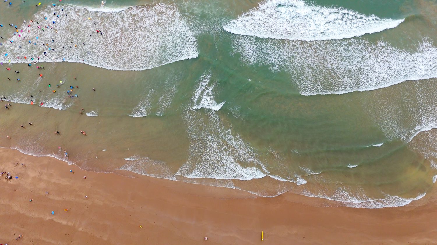 An aerial drone shot of Croyde Beach in North Devon. There are visible rip currents in the sea.
