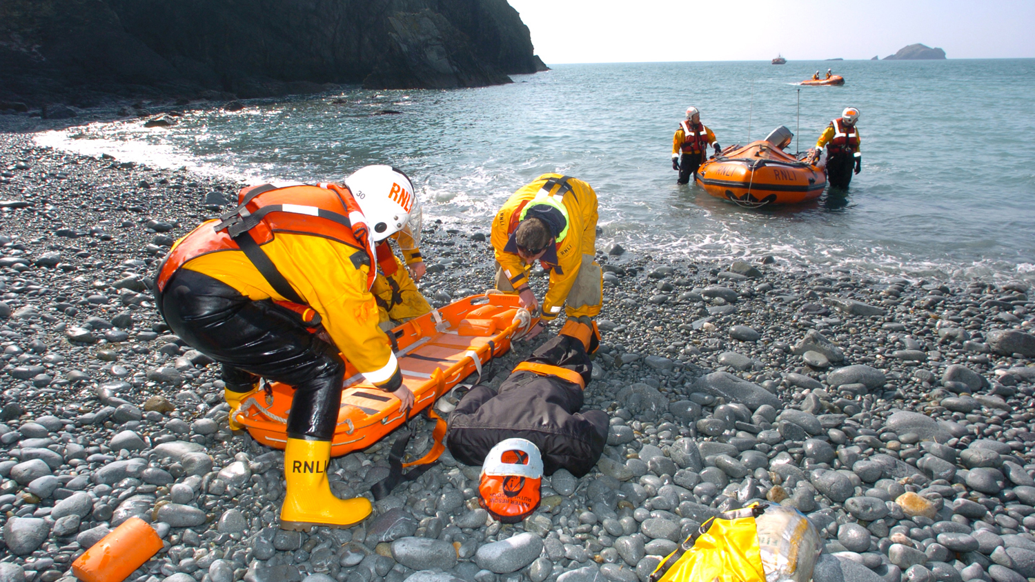 RNLI crew members putting the training manikin on a stretcher