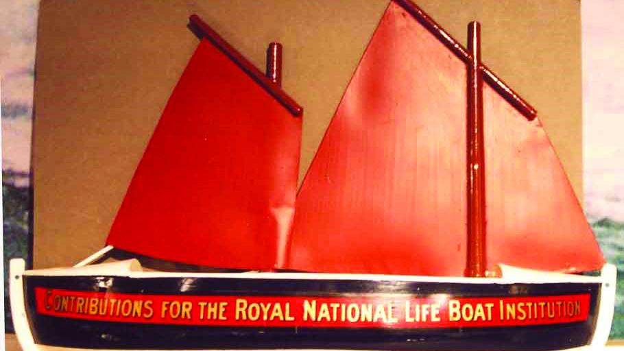 The shape of a pulling–sailing lifeboat would go on to be the basis of most collection boxes produced by the RNLI, even after the introduction of engines and more modern lifeboat designs. This classic example features the tan sails that powered lifeboats for many years.