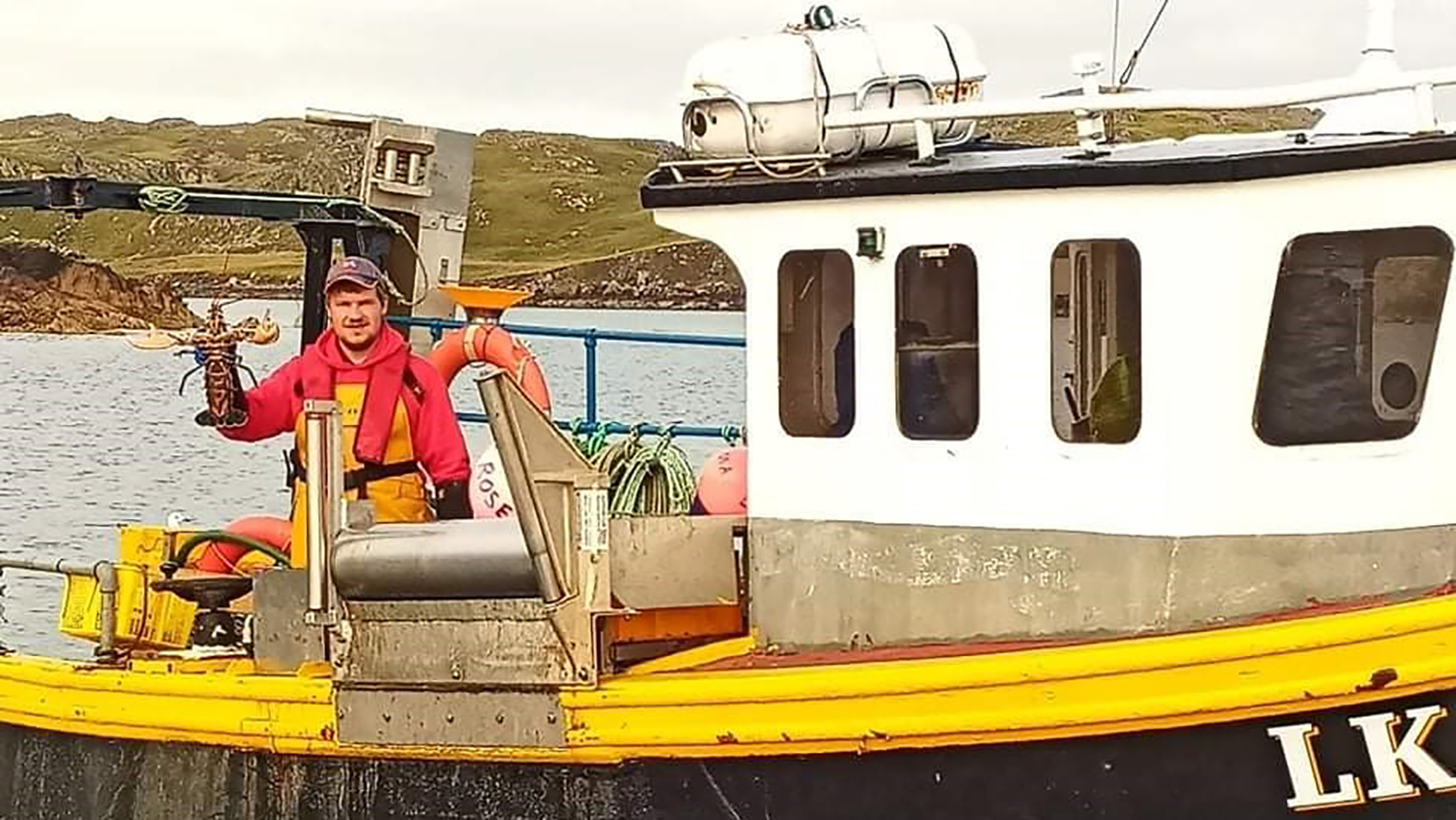 John-Arthur holds up a lobster on his new boat