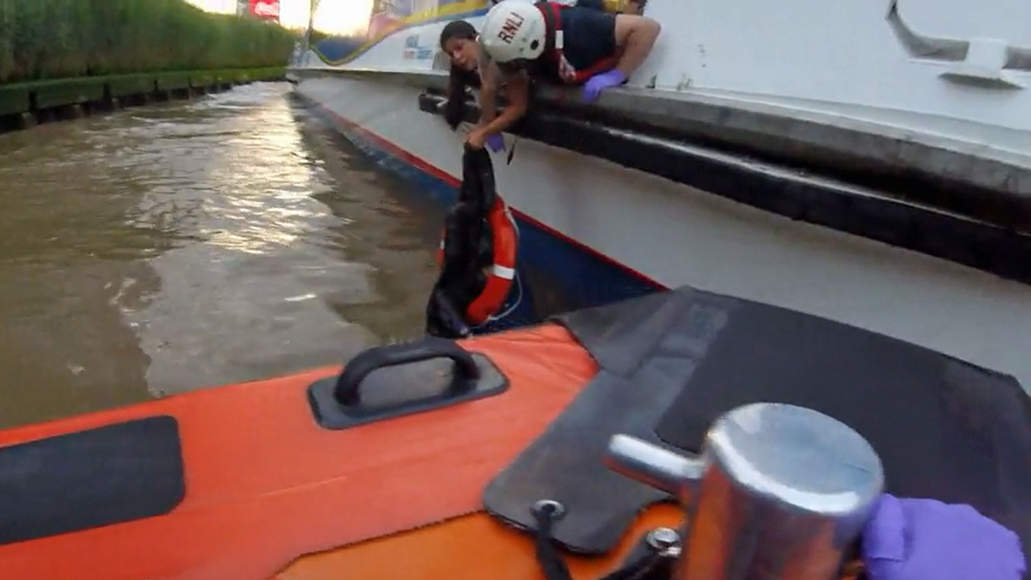View from Tower’s E class lifeboat of Holly and lifeboat volunteer Ian leaning over the Thames river bus and hanging onto the unconscious casualty who is in a lifering in the river