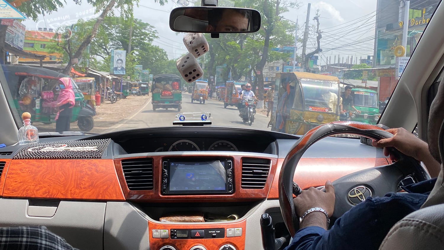 The view from the van’s dashboard, showing a busy and colourful street 