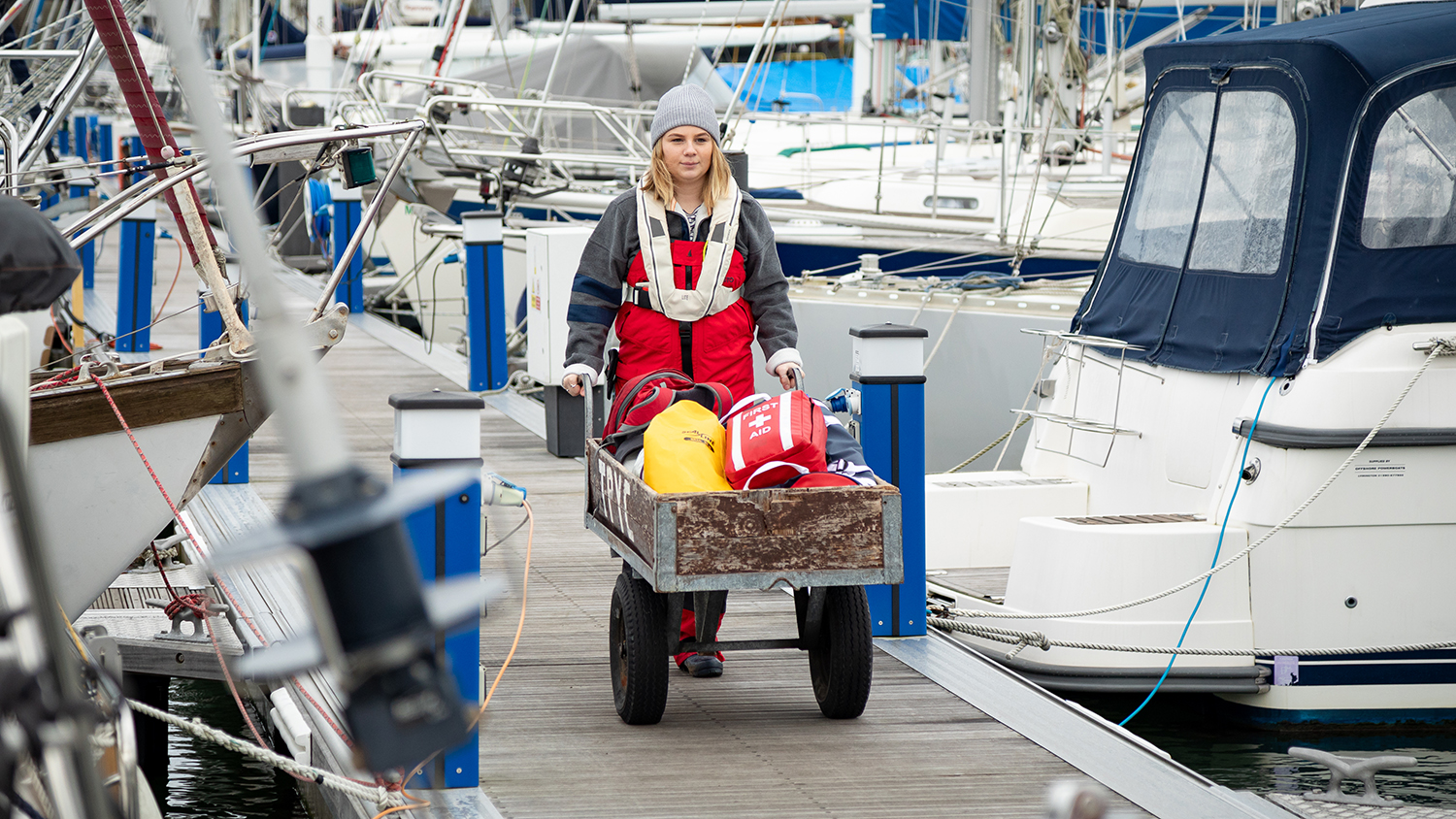 A woman dressed for winter sailing, walking down a dock