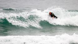 An RNLI lifeguard surfs at Porthtowan Beach in Cornwall