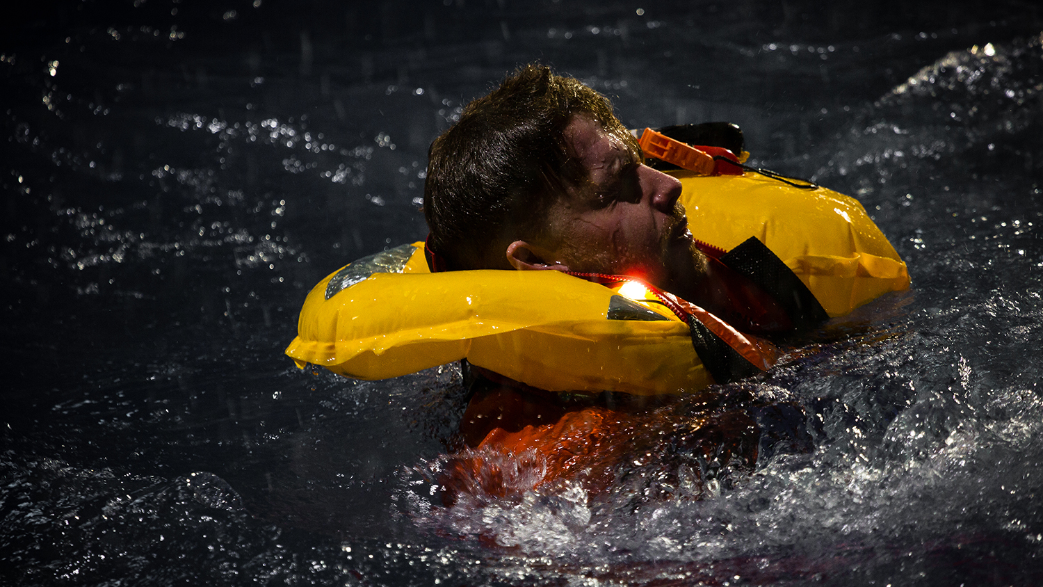 A man wearing a yellow lifejacket in the RNLI's Sea Survival Centre in Poole