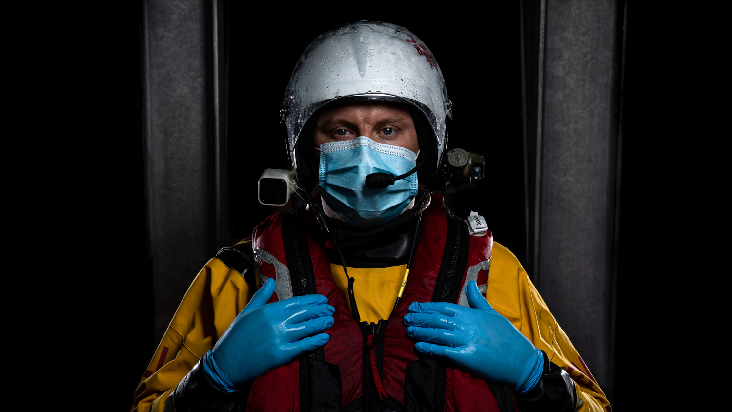 Lifeboat crew member in inshore lifeboat kit wearing a mask and blue gloves