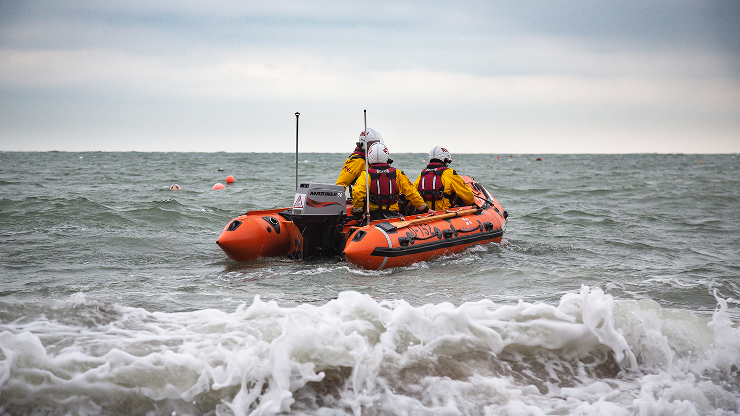 Swanage’s D class inshore lifeboat moves through the water, with three crew members aboard