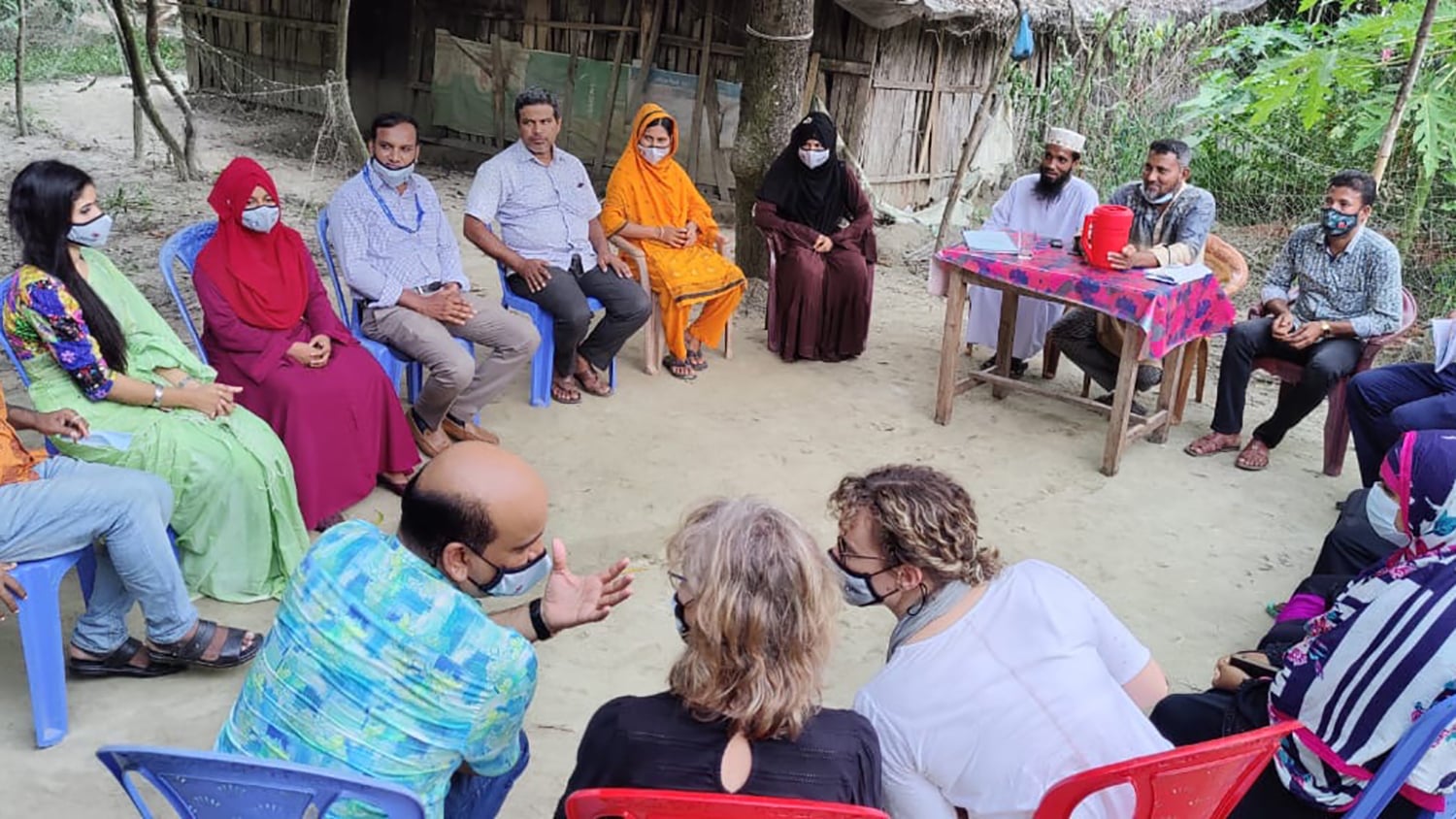 Several members of the village sit in a circle to discuss initiatives to reduce drowning