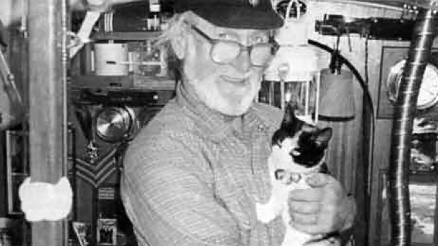 A black and white photographer of Bob Faversham holding his black and white cat