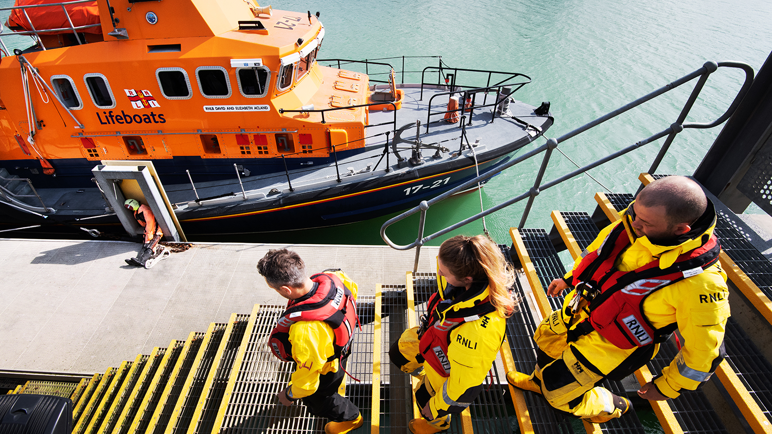 Newhaven crew walk down a set of stairs to their Severn class lifeboat, which is moored afloat in the harbour