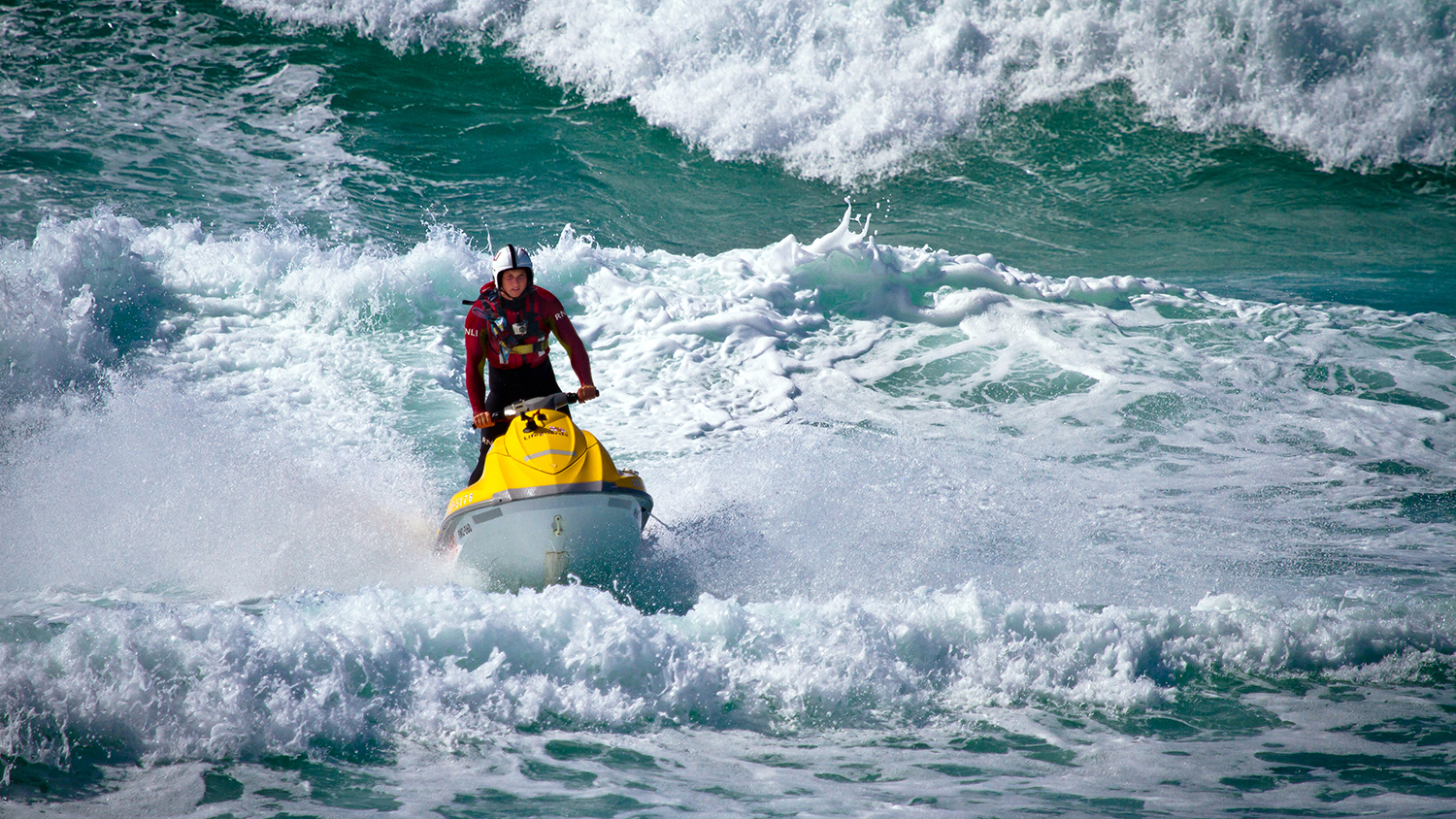 A lifeguard on a rescue watercraft in choppy surf