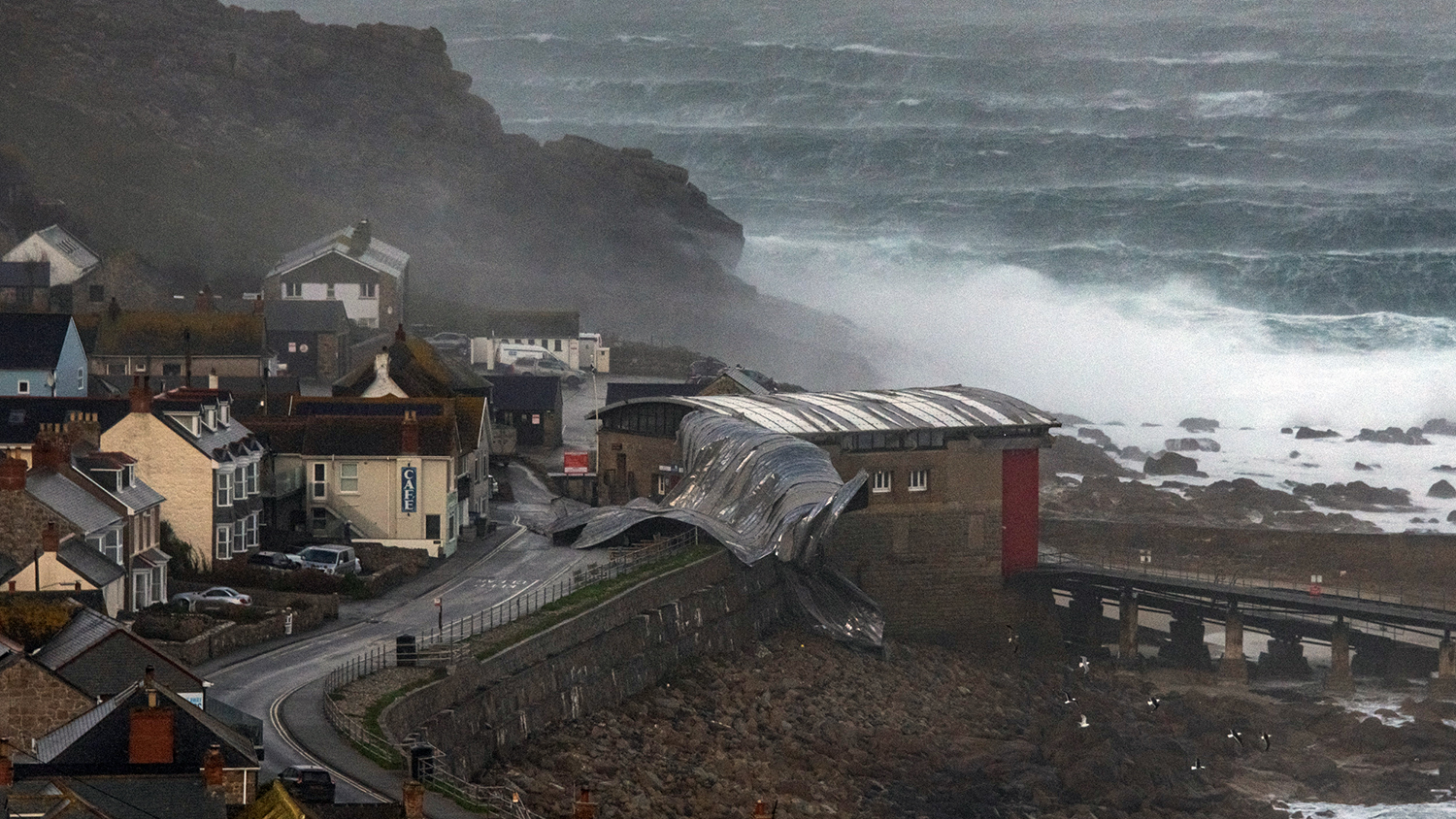 The roof of the lifeboat station has blown into the road at Sennen Cove as wind and waves attack the town