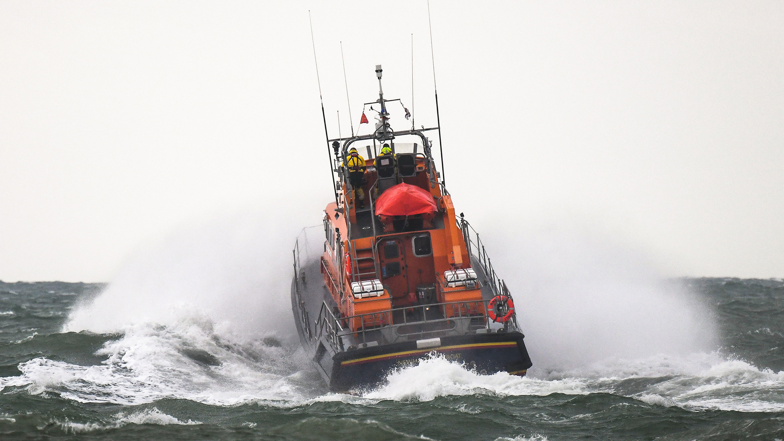 Newhaven’s lifeboat powers through the sea on a misty, grey day, with lots of spray around it