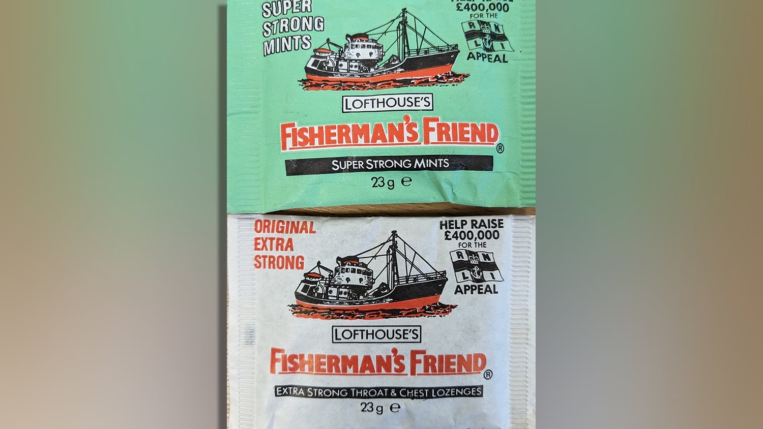 Two packets of Fisherman’s Friends lozenges. One packet is green and the other packet is white. On both packets, there is bold red text that reads, ‘Fisherman’s Friend’, as well as an illustration of a fishing boat.