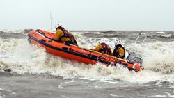 Skegness’s D class lifeboat Peterborough Beer Festival IV powers through waves on a cloudy day. There are three crew members onboard the lifeboat