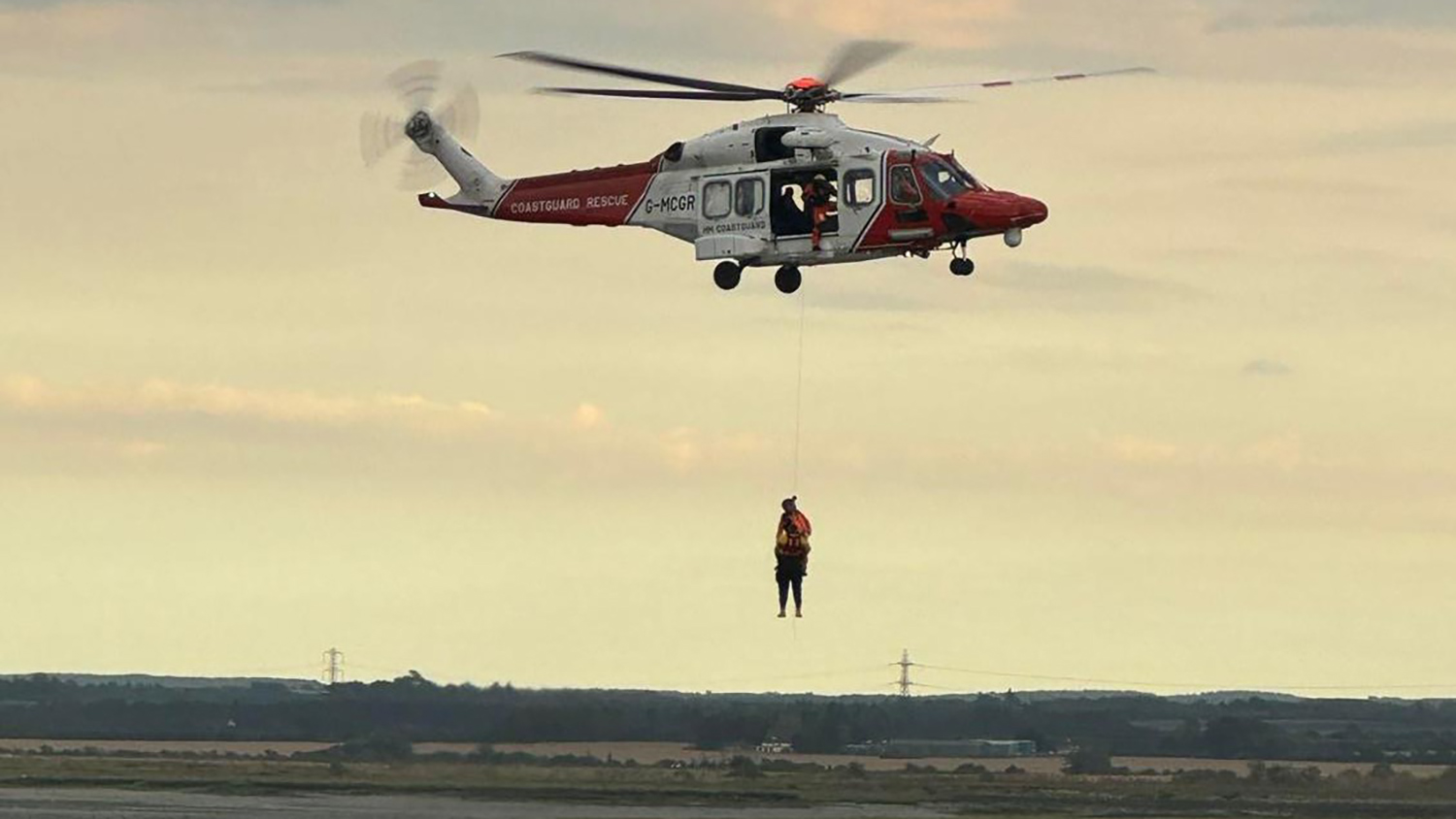 A person being winched to safety by a Coastguard Rescue helicopter