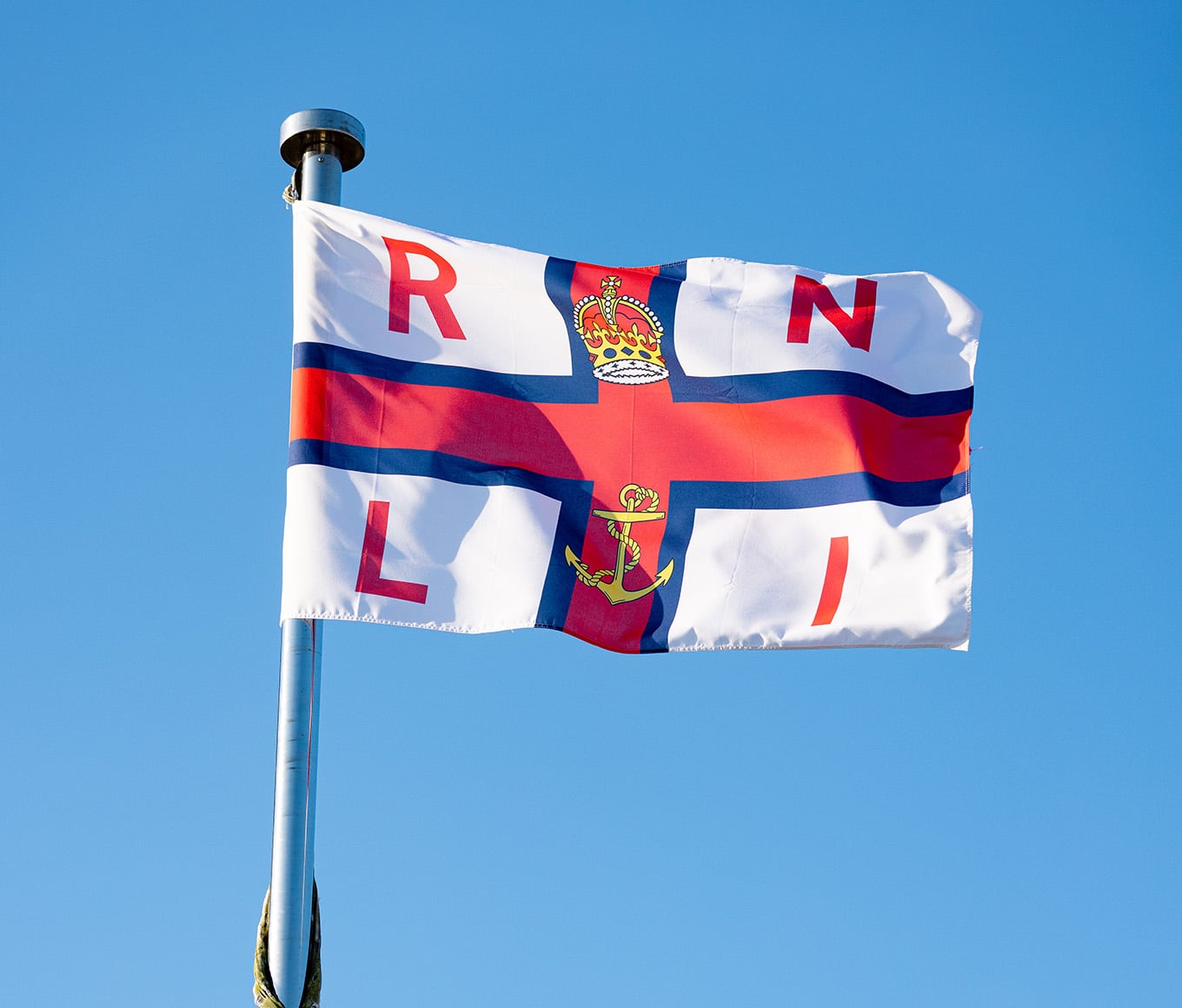An RNLI flag flying in the breeze, with a blue sky background. 