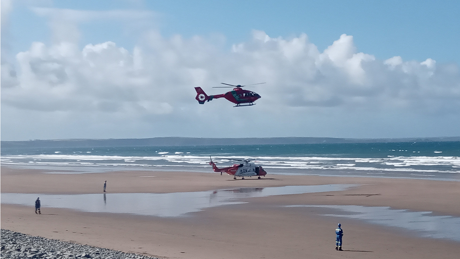 The Wales Air Ambulance and the Irish Coast Guard rescue helicopter both arrive at the beach. 