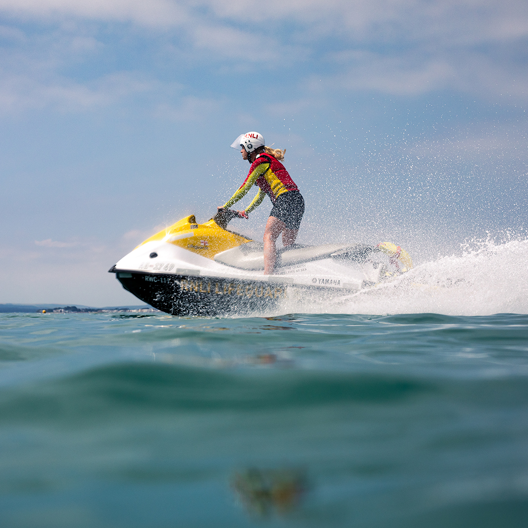 A lifeguard patrolling the beach on a rescue watercraft.