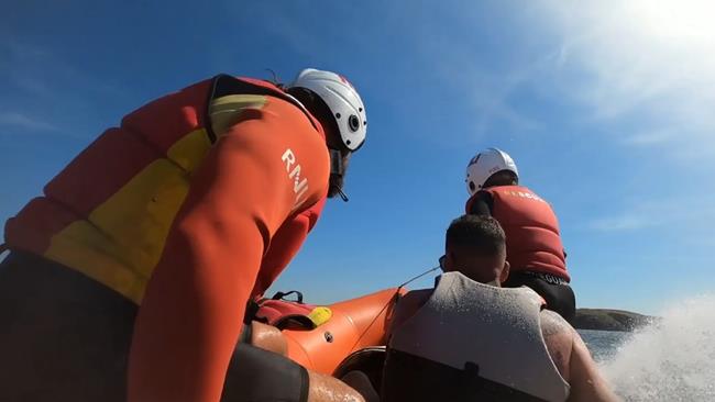 Andy sits in an inshore rescue boat, along with two RNLI lifeguards. Photo: RNLI.