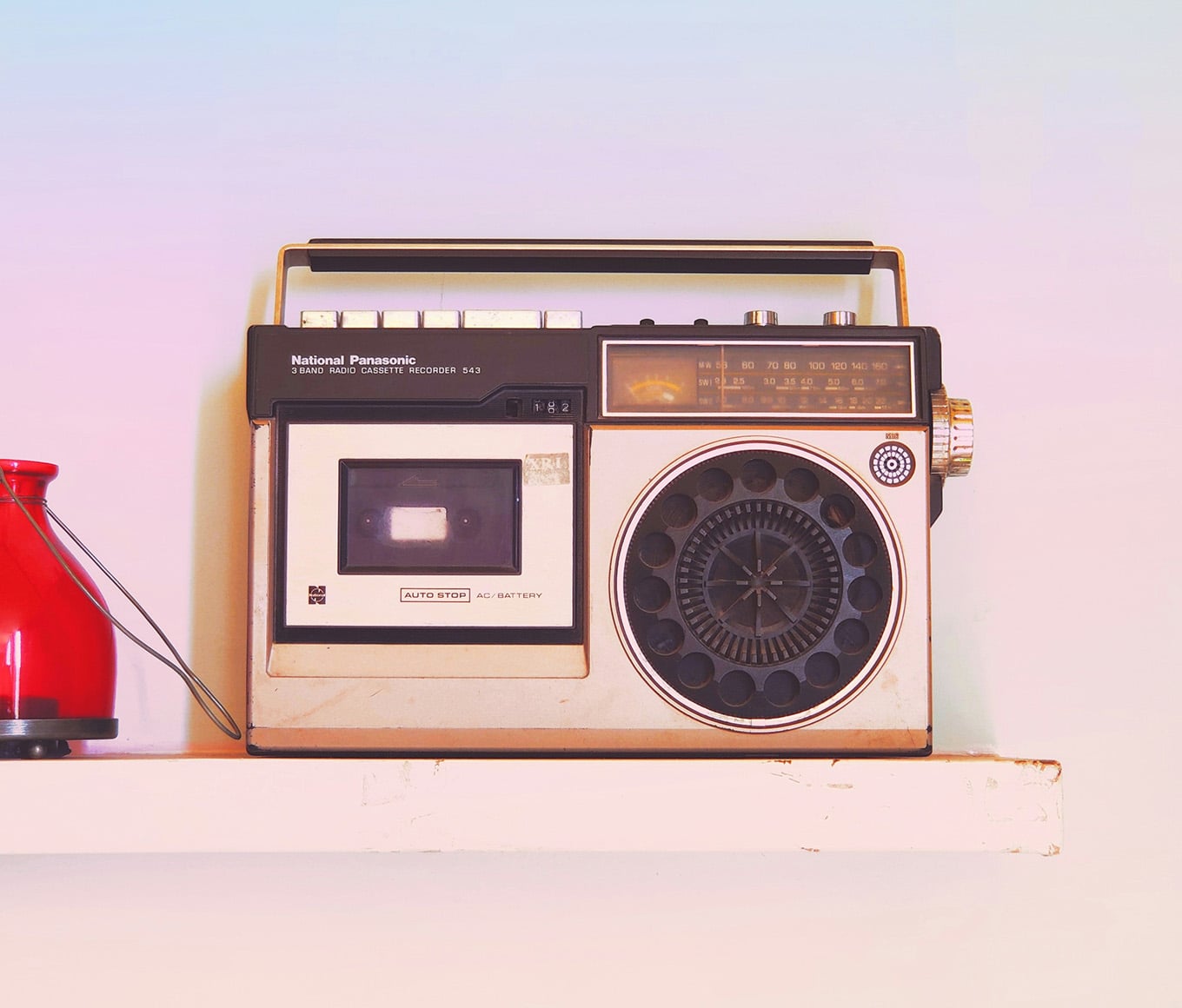 An old-fashioned radio on a pink and blue-tinged background.