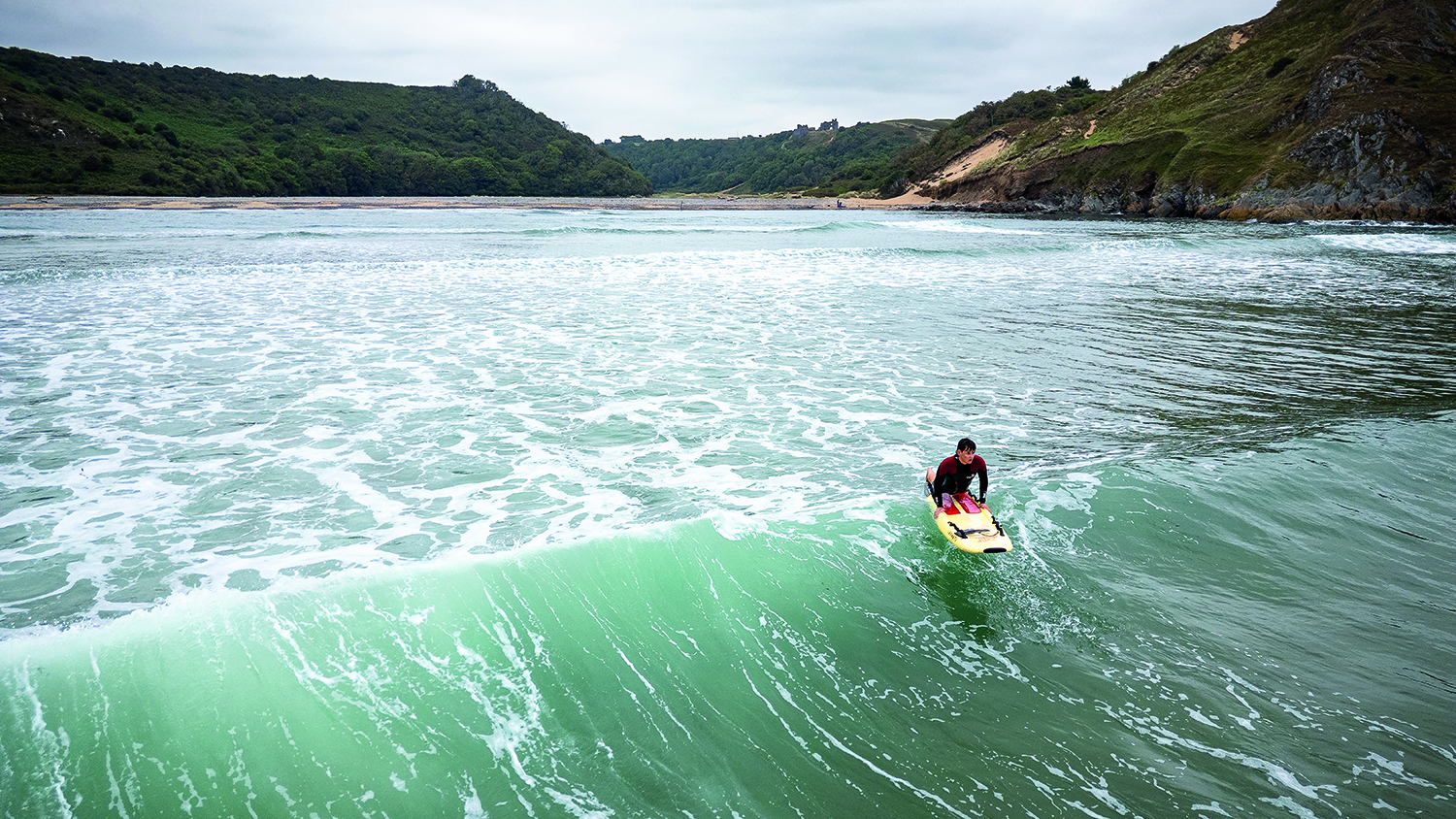 A lifeguard heading out to sea on a rescue board.