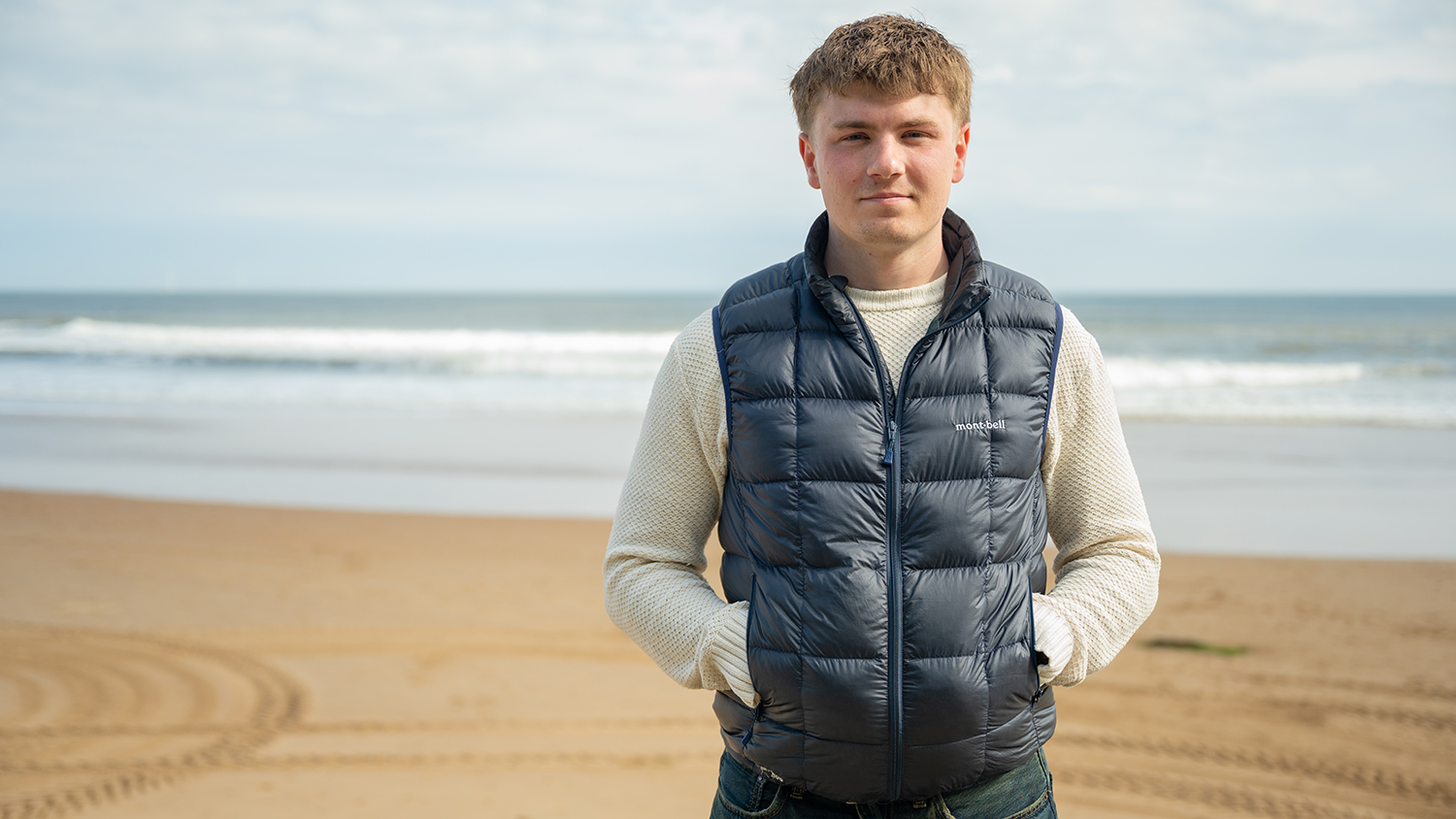 Euan stands on the sand at Longsands Beach, where he was rescued after being caught in a rip current, looking at the camera. 