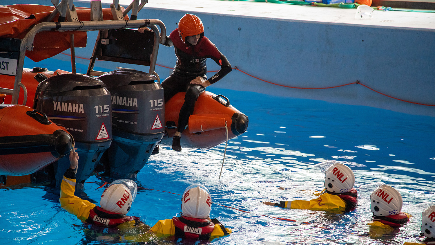 Crew members in the RNLI Sea Survival Pool with a B class Atlantic lifeboat as part of capsize training on the Crew Emergency Procedures course.