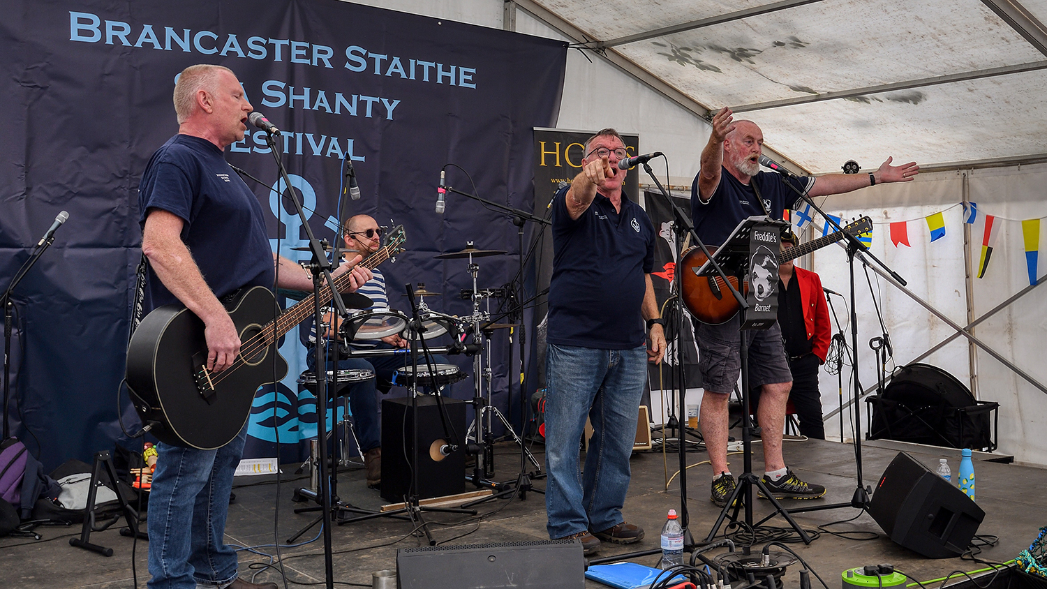 Four members of Freddie's Barnet playing together on stage at a festival. 