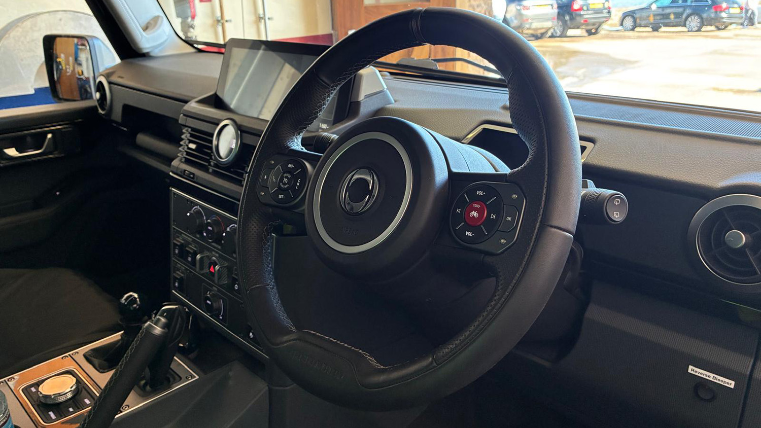 A view of the interior of the INEOS vehicle cockpit, showing the steering wheel and central controls.  