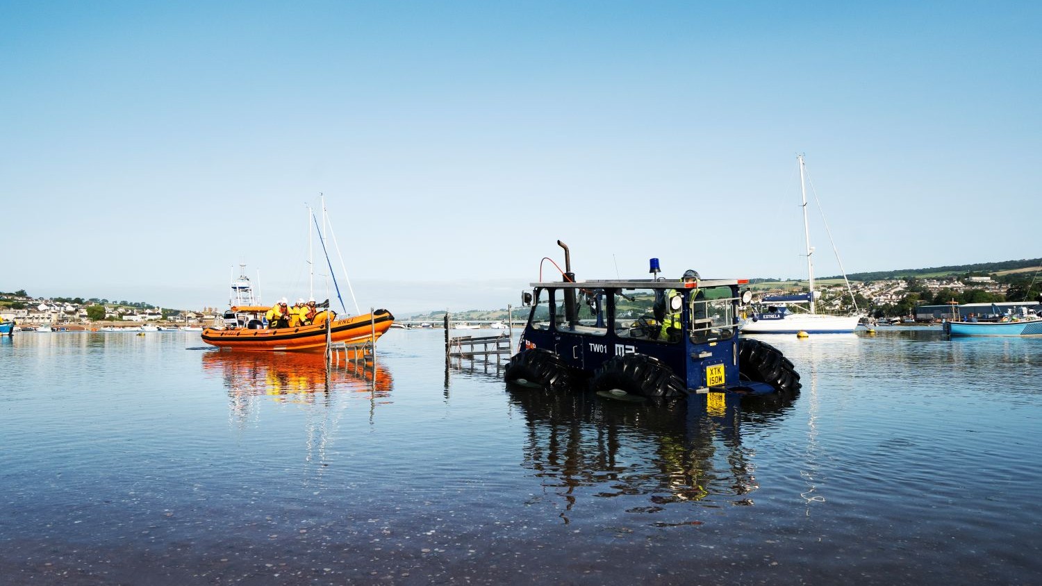 A tractor waits in calm water for an Atlantic 85 rib to drive onto a rig attached to the tractor.