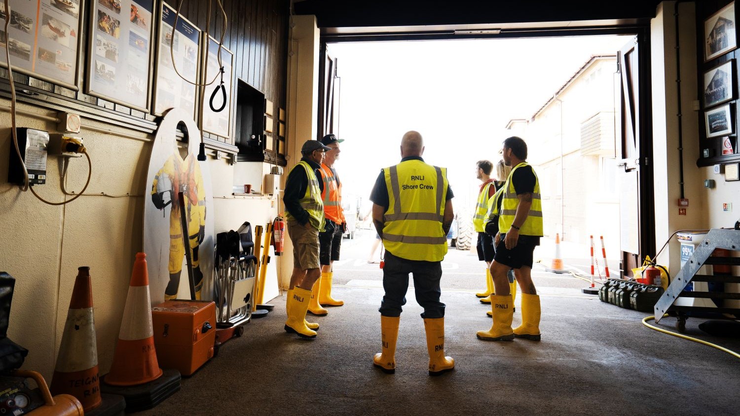 Shore crew in yellow wellies and hi-viz gather round the head launcher in orange hi-viz for a briefing.