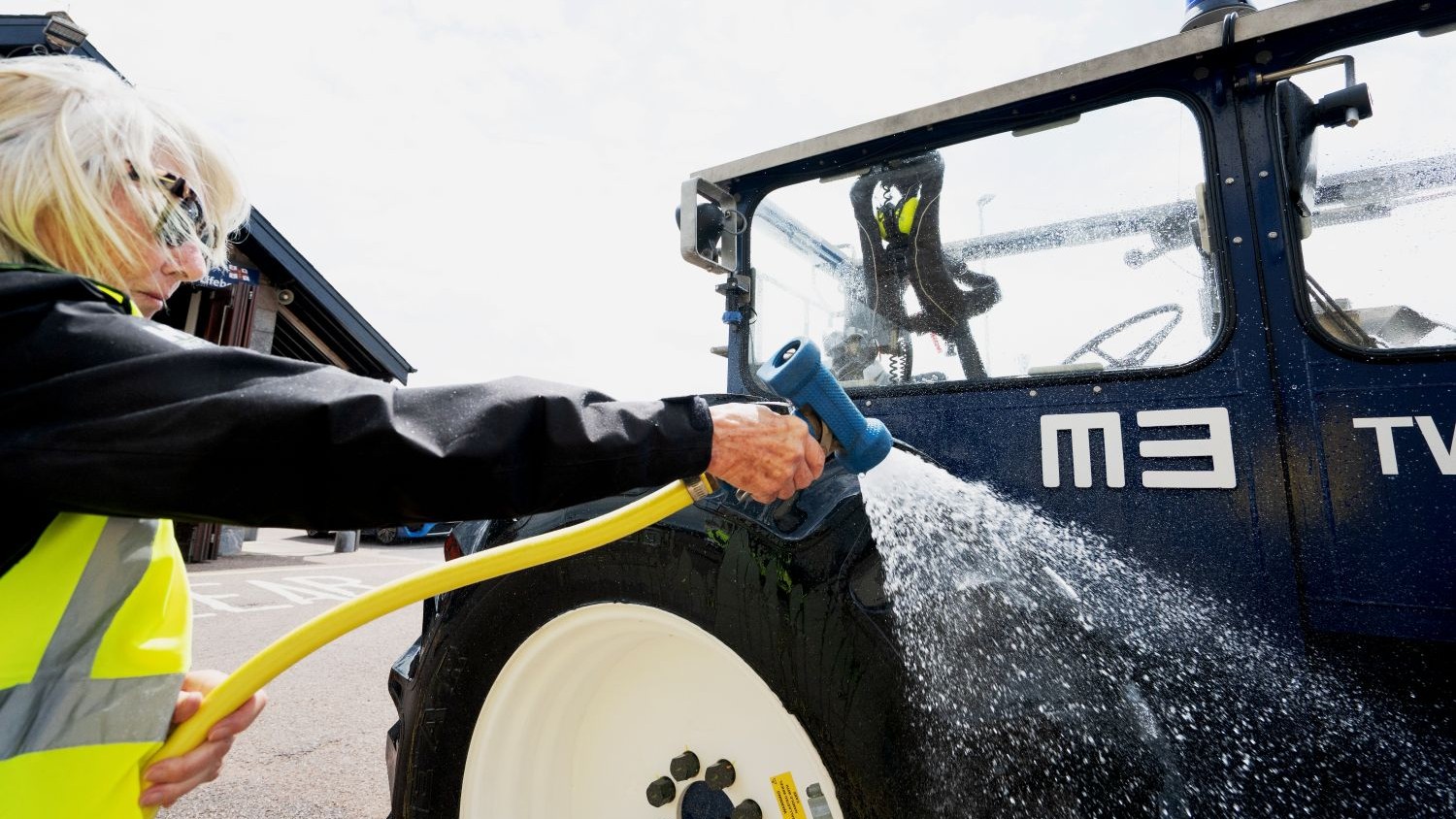Shore crew member hosing down a tractor.