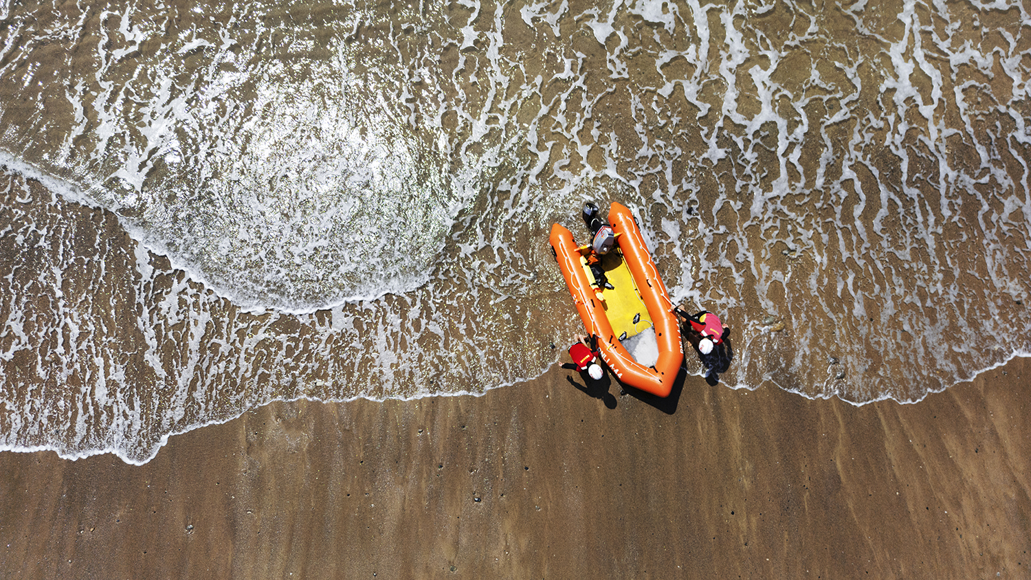 An aerial view of Praa Sands lifeguards pulling their inshore rescue boat from the sea.