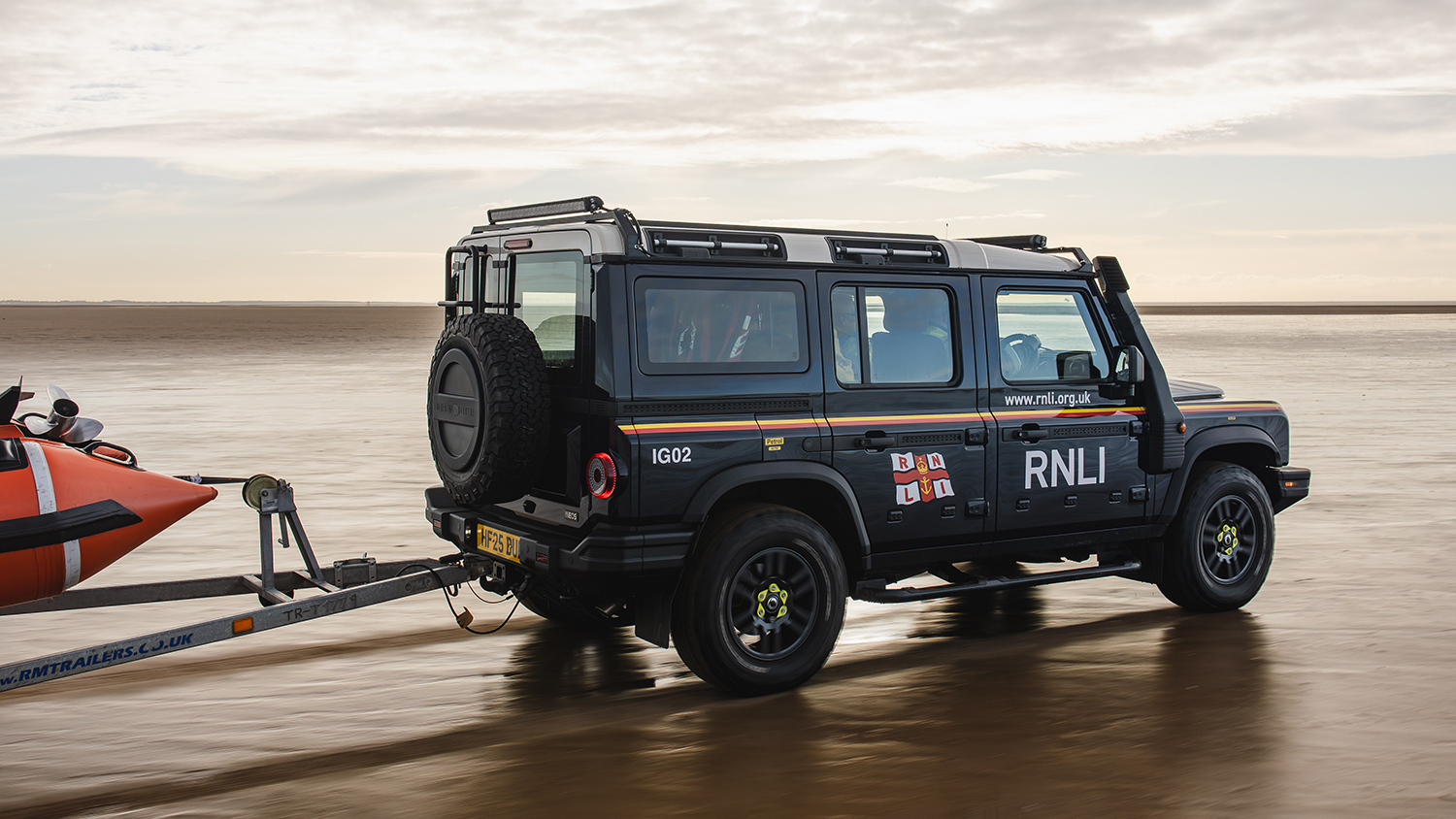 The Lytham St Annes crew driving along the sand in their new Grenadier, with their D class lifeboat attached in a trailer