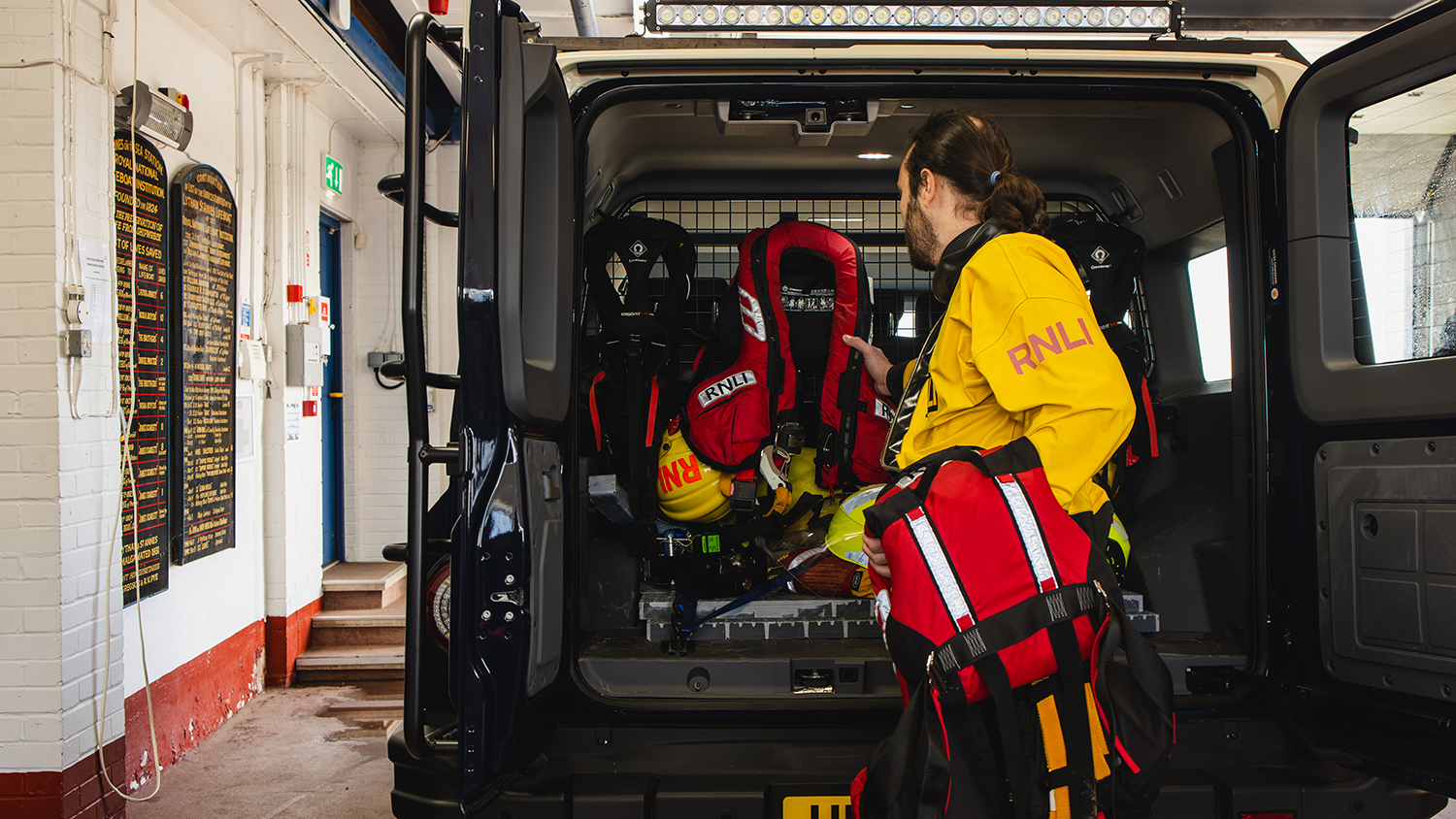 A Lytham St Annes crew member is hanging up lifejackets in the back of their INEOS Grenadier vehicle. 