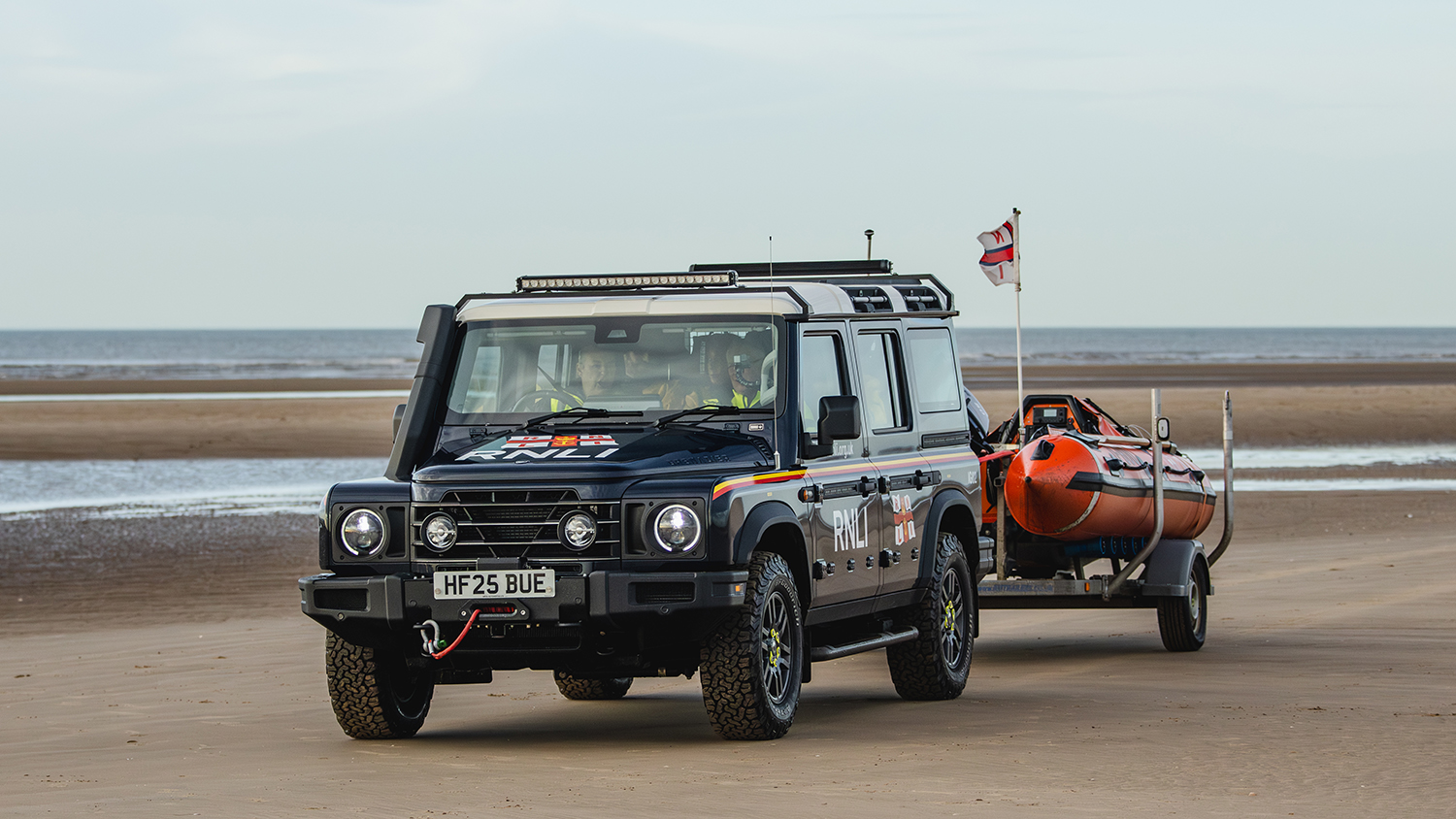 The Lytham St Annes crew driving across the sand in their new Grenadier, with their D class lifeboat attached in a trailer.
