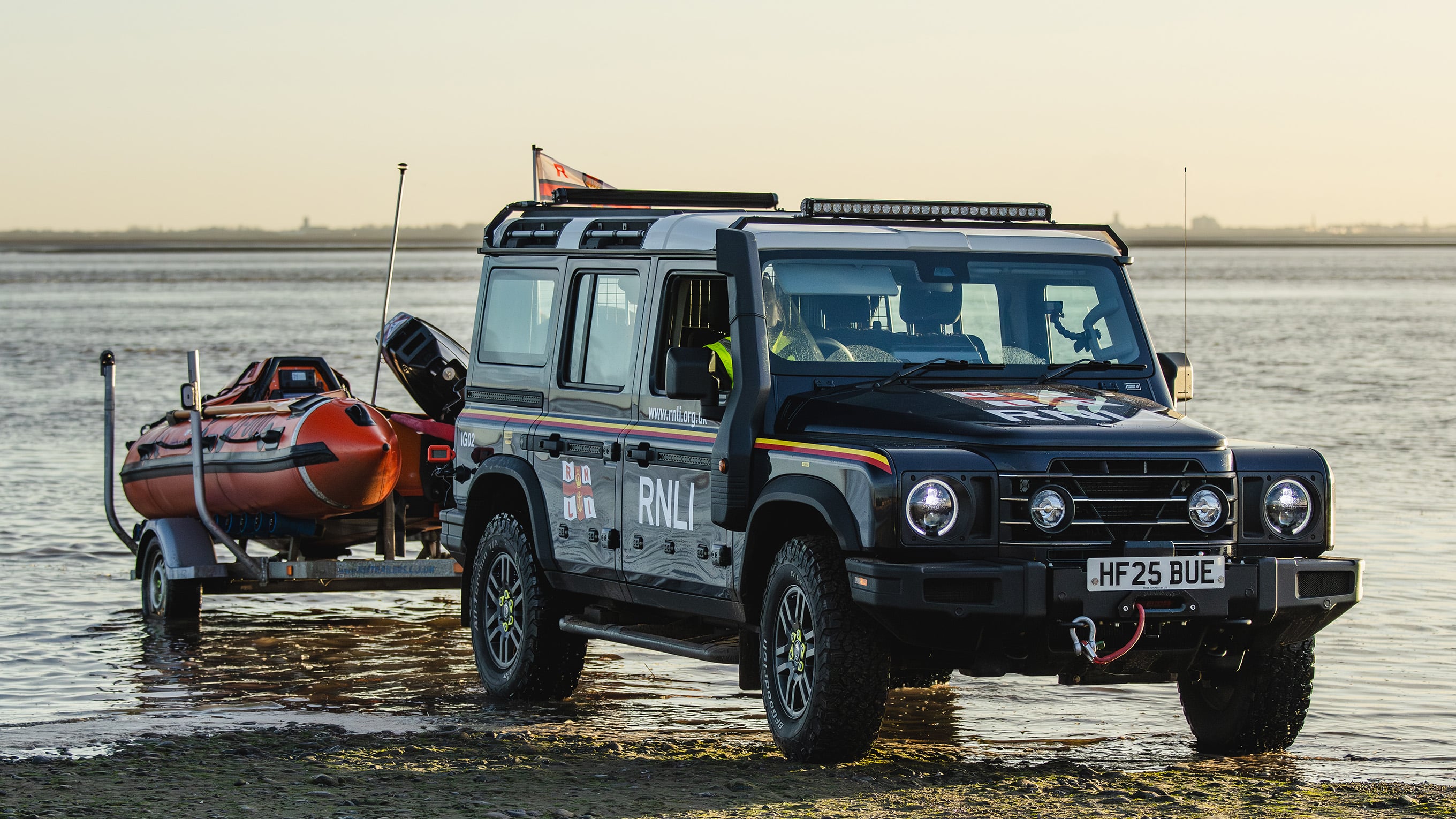 The INEOS Grenadier launch vehicle launching a D class lifeboat at the beach.