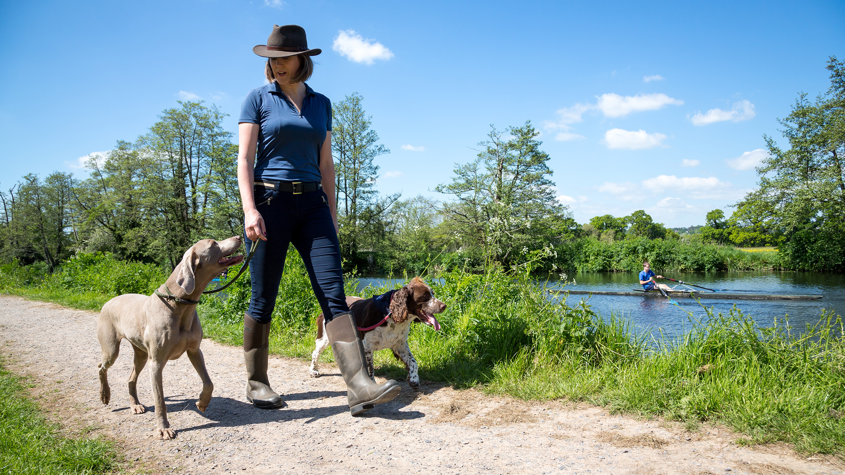A woman walking her two dogs safely along a riverbank. Credit: RNLI/Nathan Williams