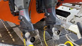 Headphone like attachments on the end of hoses over the inlets of two outboard motors.